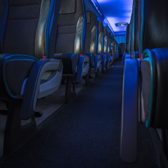 a row of charter bus seats, with blue lights on the ceiling